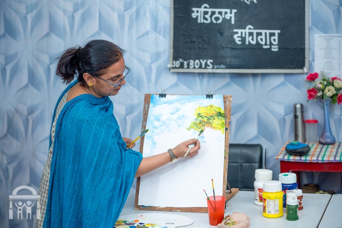 Teacher demonstrating painting in art class at Guru Nanak Mission Public School Dhahan Kaleran