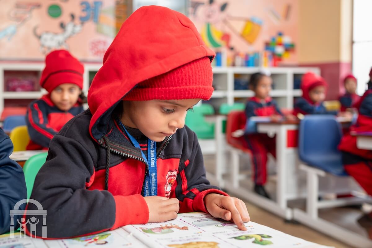 Kindergarten boy reading a book at his desk at Guru Nanak Mission Public School in Dhahan Kaleran, Punjab