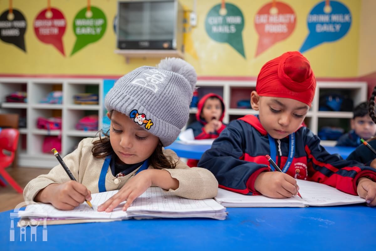Kindergarten children writing at a table at Guru Nanak Mission Public School in Dhahan Kaleran, Punjab