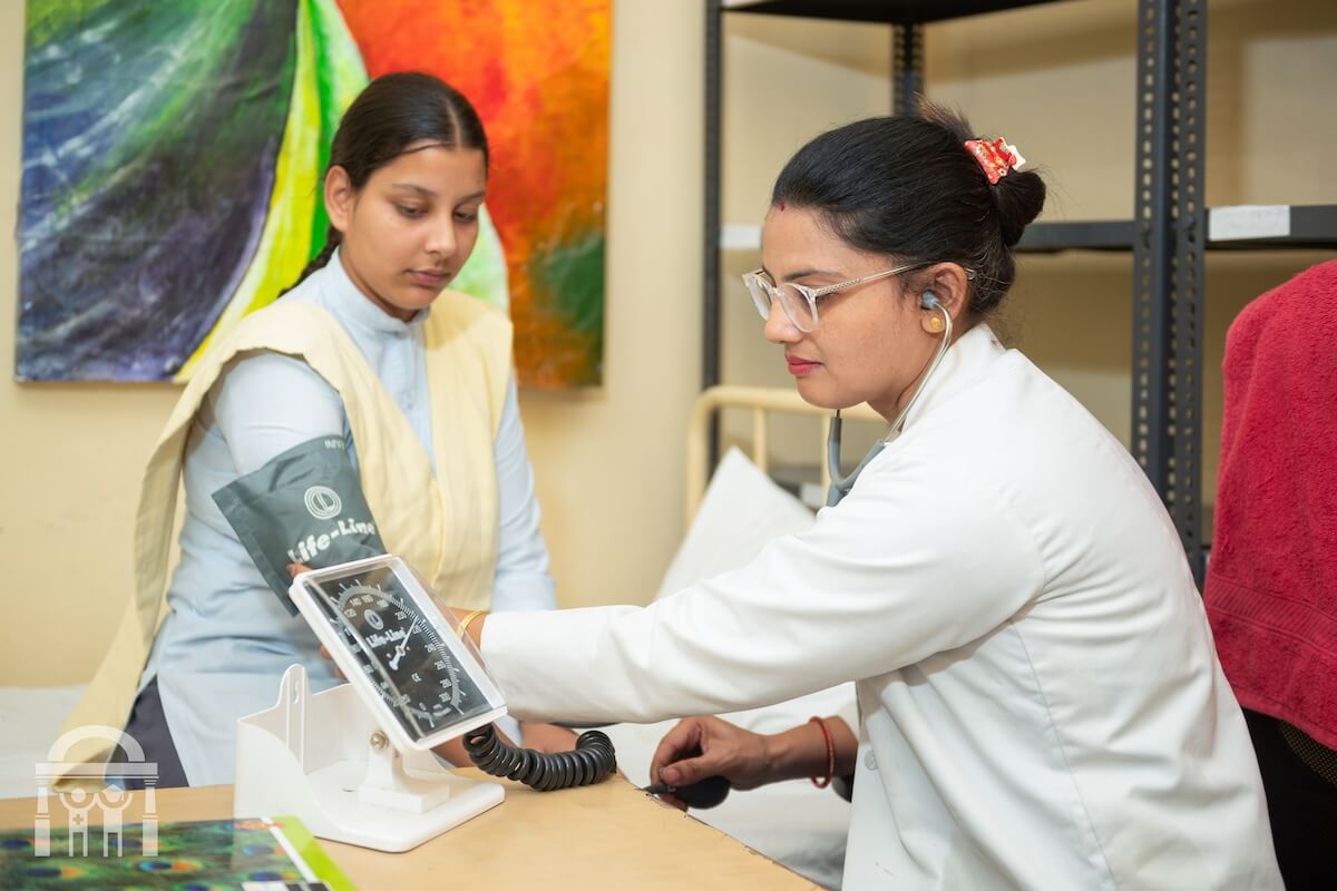 School nurse checking blood pressure of high school girl